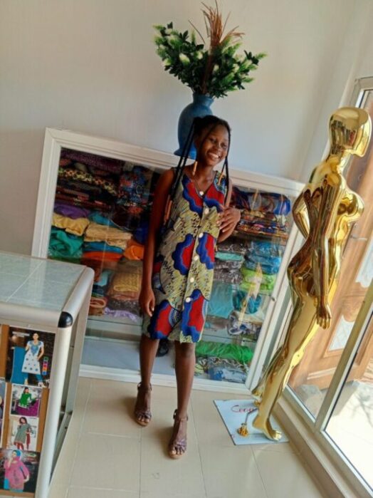 Portrait de PROSPERA, entrepreneure textile, souriante et prête à innover.